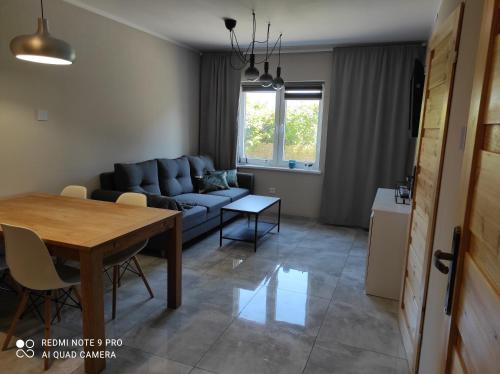 ein Wohnzimmer mit einem Sofa und einem Tisch in der Unterkunft Apartament Spokojny in Mielno