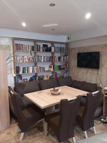 a table and chairs in a living room with bookshelves at Egniss Apartman 2 in Bogács