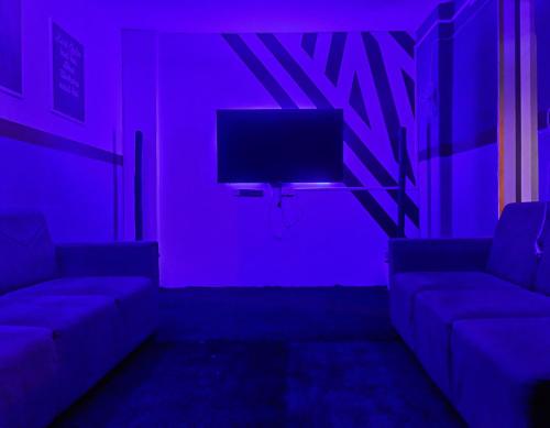 a purple room with a couch and a tv at Procida Hostel by Zero Jhanjhat in Pune