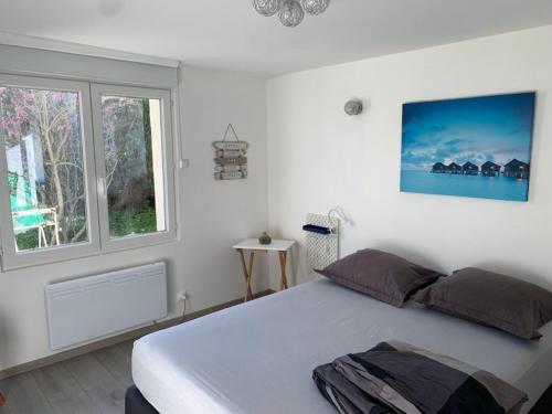 a white bedroom with a large bed and a window at studio 2 personnes in Luxeuil-les-Bains