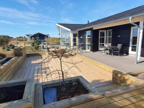 een houten terras met een tafel en stoelen op een huis bij 8 person holiday home in L kken in Løkken