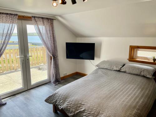 a bedroom with a bed and a flat screen tv at Holmview apartment in Stornoway