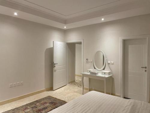 ein weißes Schlafzimmer mit einem Bett und einem Spiegel in der Unterkunft سمو 4 in Riad