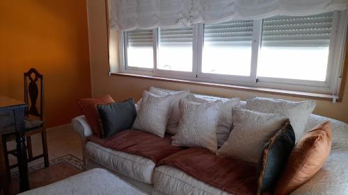 a couch with pillows in a living room with a window at Casa rural El Abuelo Arturo in Becerril de la Sierra