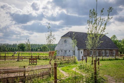 an old barn in a field with a fence at B&B Hoeve Klein Haneveld in Sint-Oedenrode