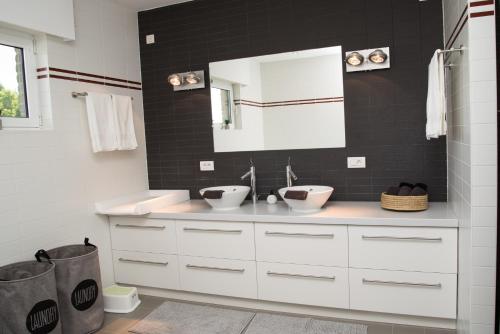 uma casa de banho branca com 2 lavatórios e um espelho em casa tibella em Ichtegem