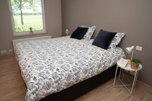 a bedroom with a bed with a blue and white comforter at casa tibella in Ichtegem