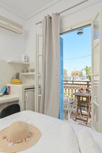 a hat on a bed in a room with a balcony at Katy's Home in Naxos Chora