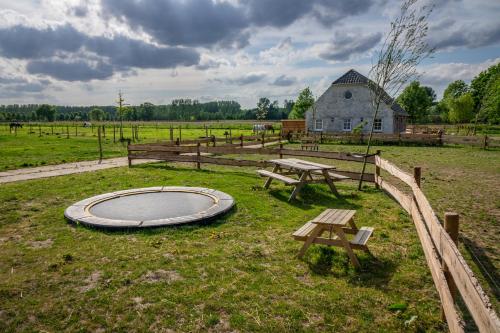 a picnic table and benches in a field with a barn at B&B Hoeve Klein Haneveld in Sint-Oedenrode