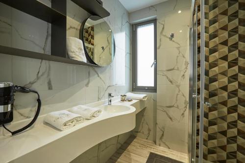 La salle de bains blanche est pourvue d'un lavabo et d'un miroir. dans l'établissement GreyStone Suites, à Paralia Dionisiou