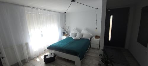 a bedroom with a bed with a green blanket and a window at Apartamenty Pod Uwalonym Dębem in Jeżów Sudecki