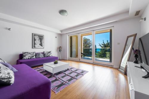 ein Wohnzimmer mit einem lila Sofa und einem Tisch in der Unterkunft Apartments Dvori Lapad 2 Direct Sea View in Dubrovnik