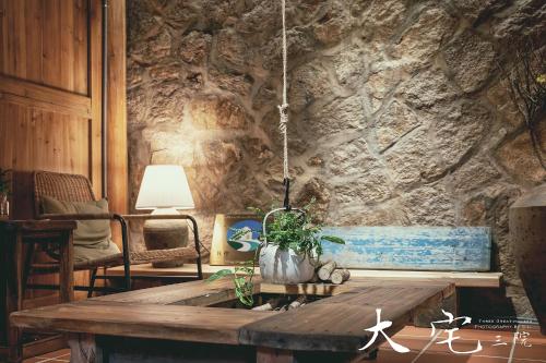 a room with a wooden table and a stone wall at 大宅三院青年旅舍 背包客棧 in Beigan