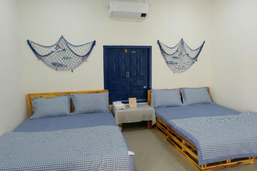a room with two beds and a table and a door at Homestay Miền Biển Vĩnh Hy in Vĩnh Hy