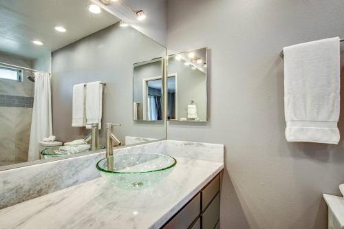 baño con lavabo de cristal y espejo en Great Vibe House + Hot Tub, Minutes to JTree Park, en Twentynine Palms