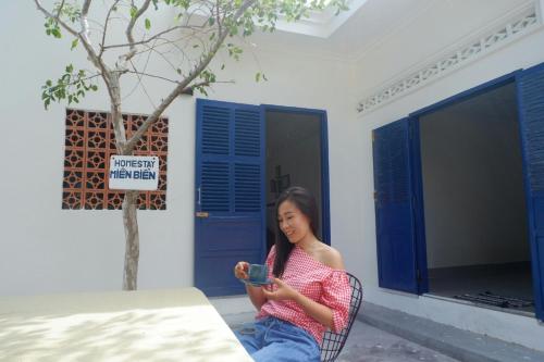 a woman sitting in a chair looking at her cell phone at Homestay Miền Biển Vĩnh Hy in Vĩnh Hy