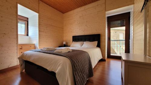 ein Schlafzimmer mit einem großen Bett in einem Zimmer mit Holzwänden in der Unterkunft Casa do Quinteiro in Arcos de Valdevez
