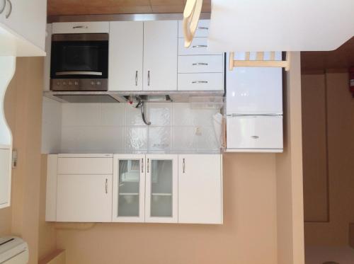a kitchen with white cabinets and a microwave at Boutique Hotel Ileas Village in Arkoudi
