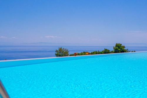 a blue swimming pool with the ocean in the background at Lamar Private Luxury Villas in Marathias
