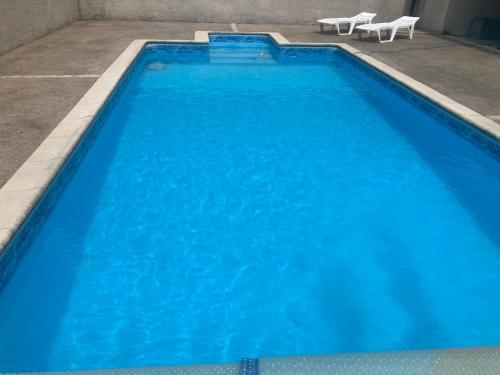 a large blue swimming pool with two chairs in it at Gîte le verger in Soulignonne