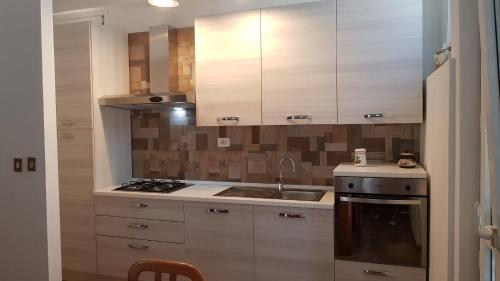 eine Küche mit weißen Schränken, einer Spüle und einem Herd in der Unterkunft VILLETTA INDIPENDENTE in Alba Adriatica