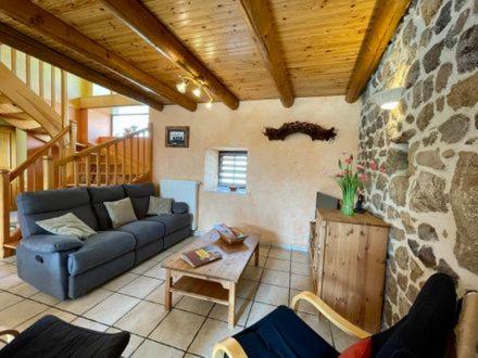 a living room with a couch and a stone wall at gite La Fermette in Valprivas