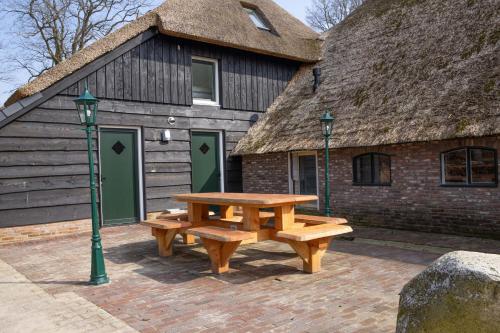 a wooden picnic table in front of a building at erve Middendorp in Ansen