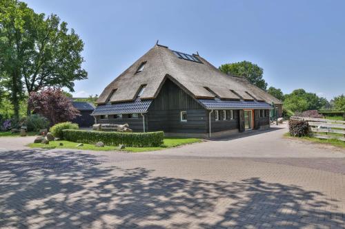 a large building with a thatched roof on a street at erve Middendorp in Ansen