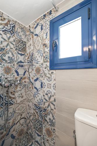 a bathroom with a blue window and a toilet at Katy's Home in Naxos Chora