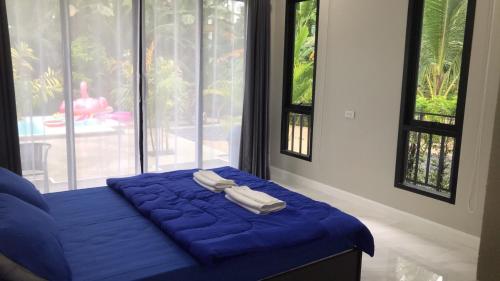 Una cama azul con dos toallas encima. en Pool Villa Nita, en Ban Na Klang