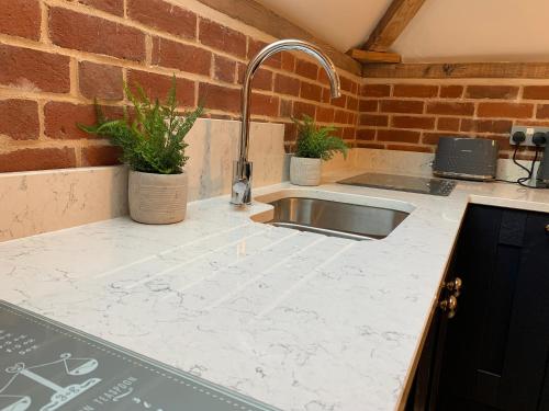 a kitchen counter with a sink and a brick wall at Unique Countryside Retreat, walking distance to the Three Choirs Vineyard & Restaurant, Gloucestershire in Newent