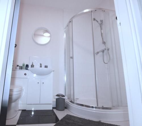 a white bathroom with a shower and a toilet at Spacious, 3 Bedroom Contractor Apartment with Parking in Newport Pagnell Town Centre by Maison 19 in Milton Keynes