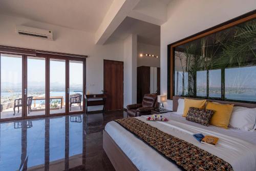 a bedroom with a large bed with a large window at StayVista at Sunset on the Lake - Infinity Lakeview Swimming Pool with Contemporary Interiors & Lavish Amenities in Igatpuri