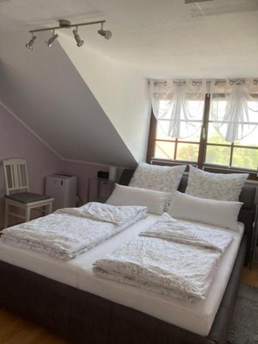 una camera da letto con un letto con lenzuola bianche e una finestra di Ferienwohnung Knittel a Kallstadt