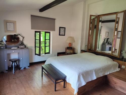 une chambre avec un grand lit blanc et un miroir dans l'établissement Chambre d'hôtes Le Moulin de Moulis, à Moulis-en-Médoc