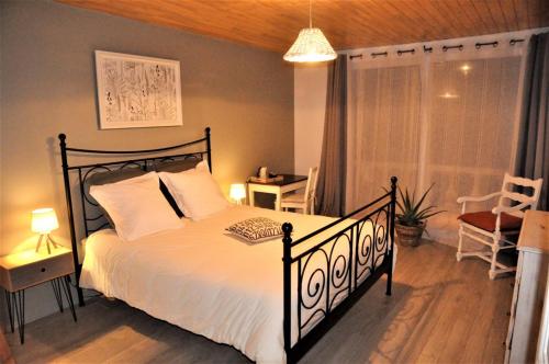 um quarto com uma cama com lençóis brancos e uma janela em Le Hangar em Saint-Jean-dʼAngély