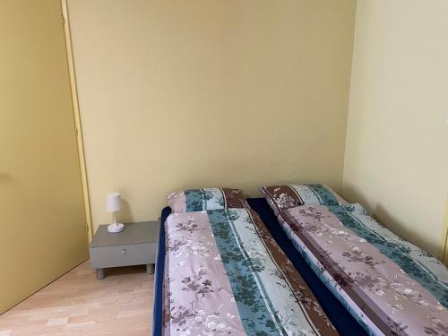 2 Betten in einem kleinen Zimmer mit einem Nachttisch in der Unterkunft Studio Neptun 4 im Zentrum von Bad Ragaz in Bad Ragaz