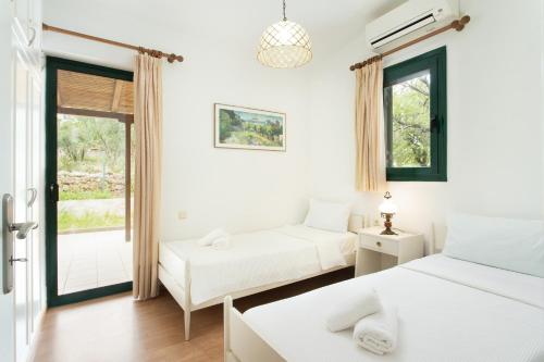 een slaapkamer met 2 bedden en een raam bij Eleni's House Cozy 2-Bedroom House with Garden in Monemvasia