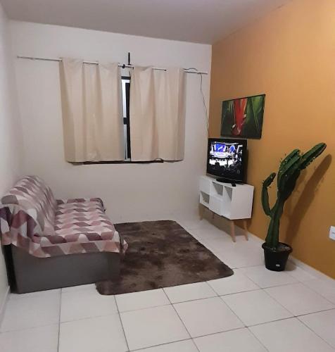 a living room with a chair and a tv at Apto Aeroporto Vilage in Macaé