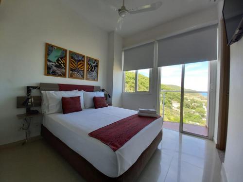 a bedroom with a large bed and a large window at Terrazas Tayrona Travelers Apartamentos y Suites in Santa Marta