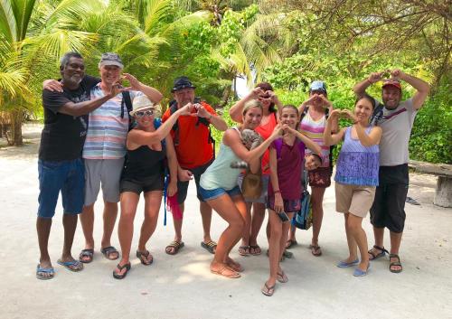 a group of people posing for a picture on the beach at Three Hearts Guesthouse and Villas in Fulhadhoo
