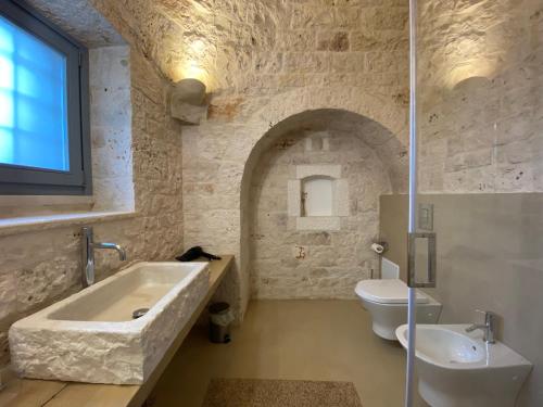 un bagno con vasca, WC e lavandino di Trulli sull'Aia San Michele a Monopoli