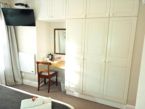 a bedroom with a desk and a large white closet at 137 High Street Guest House in Grahamstown