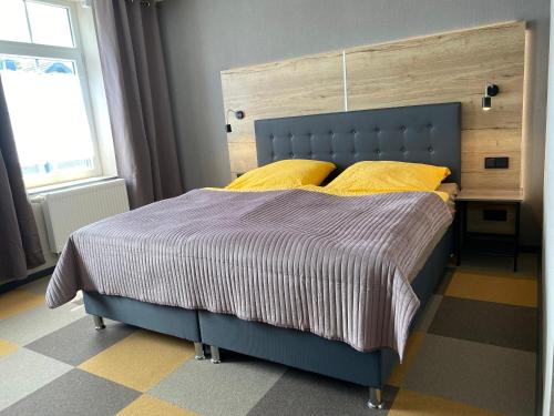 un letto blu con cuscini gialli in una camera da letto di Gästehaus Bendsieferhof a Monschau
