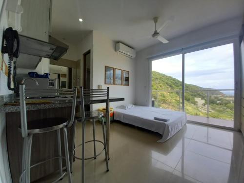 a bedroom with a bed and a kitchen with a window at Terrazas Tayrona Travelers Apartamentos y Suites in Santa Marta