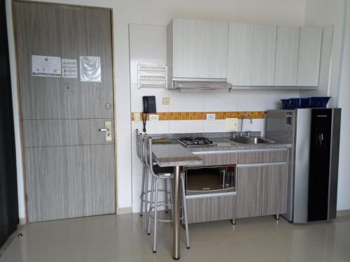 a small kitchen with a stove and a refrigerator at Terrazas Tayrona Travelers Apartamentos y Suites in Santa Marta