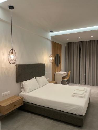 een slaapkamer met een groot wit bed en een bureau bij George Deluxe Apartments in Stalida