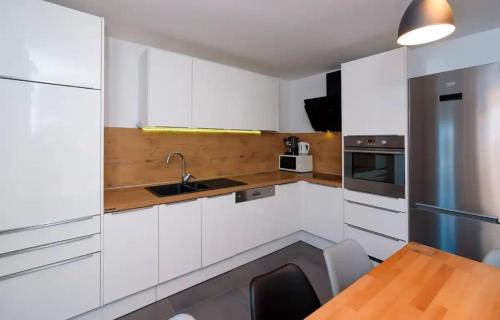 une cuisine avec des placards blancs et une table en bois dans l'établissement Apartments Magli, à Kaštela