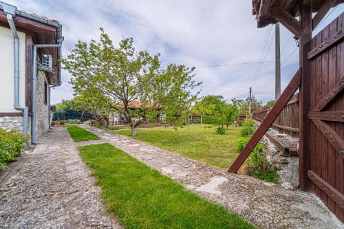 a barn door with a grassy yard next to a house at Къщата с Кладенеца - с. Генерал Кантарджиево in General-Kantardzhievo