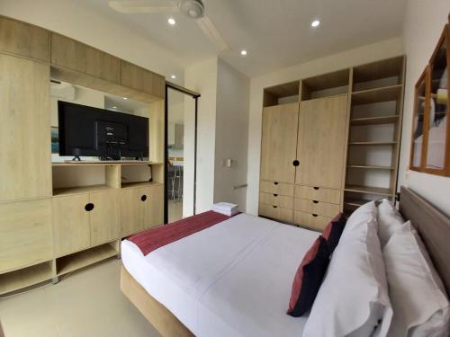 a bedroom with a large white bed and a television at Terrazas Tayrona Travelers Apartamentos y Suites in Santa Marta